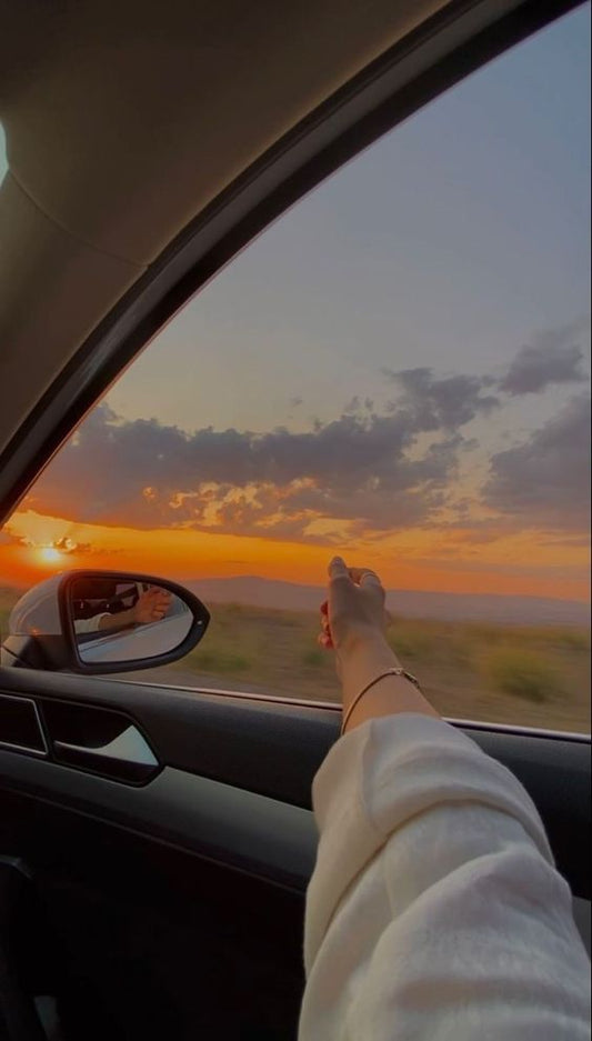 Persons hand out of a car, driving, sunset, wind blowing